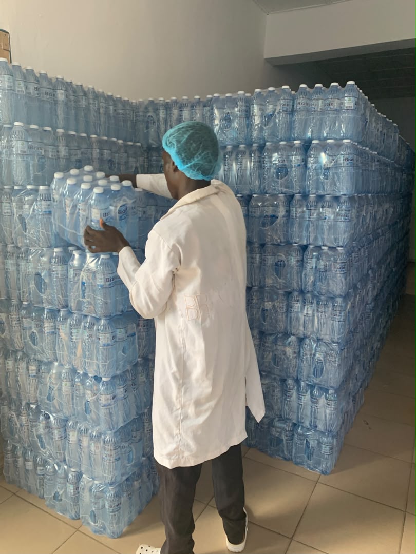 Brate quality operator inspecting shrink-wrapped bottle packs in hygienic PPE